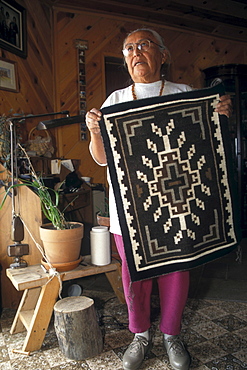 A Navajo weaver holds a rug in her home near Shiprock, New Mexico on the Navajo Indian Reservation.