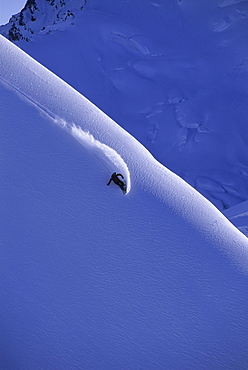 Julie Zell carving big mountain turns turns on her snowboard in Valdez, Alaska.