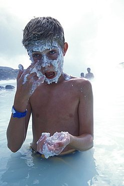 An American boy enjoys the healing powers of mud at the Blue Lagoon, near Reykjavik, Iceland.