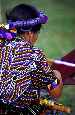 Woman in traditional huipil hand-weaving, Antigua, Guatemala.