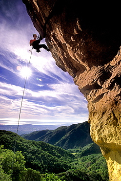 Shannon Black, silhouetted against the sky, rapells the overhanging face of Gibraltar Rock in Santa Barbara, California on January 18, 2003. The view looks south over Rattlesnake Canyon to the Pacific Ocean beyond. (Photo by Kevin Steele, Aurora)