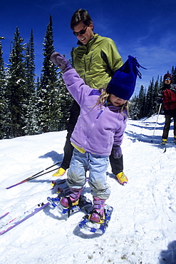 A father, Brad Piehl, watches while his daughter, Jenna, snowshoes for the first time, on the snow covered Boreas Pass Road, a popular winter recreation trail for cross country skiers and snowshoers.  The road becomes a trail, and is part of the Rails to Trails system.  It follows an old railroad grade southeast over the mountains to the town of Como.