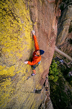 Bruce Miller climbs on the hardest part, or "crux", of a route called "Jules Verne", rated 5.11a, high off the ground on the Redgarden Wall in Eldorado Canyon State Park, CO.  Jules Verne is one of the more famous traditional or "trad" routes in the area, and has long sections between protection. Eldorado Canyon, located on the Front Range south of Boulder, and  its steep, difficult sandstone cliffs attract climbers from around the country and the world, making it one of  the most popular climbing areas in Colorado.