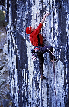 Thirteen year old Scott Cory rock climbing, lead climbing , free climbing a 5.11 route at Mayhem Cove in the Sierra Nevada Mountains, Lake Tahoe, California.