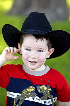 A little boy wears a black cowboy hat.