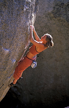 Rock climber Kelly Doyle climbing an overhanging bouldering route in the Buttermilks, outside of Bishop, California in the Sierra Nevada mountains near Hwy 395.