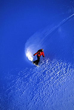 Professional snowboarder Barrett Christy snowboarding in the backcountry on a bluebird powder day, Mt Baker, Washington.