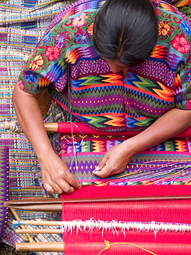 A woman from an indigenous community in Guatemala weaving while wearing an indigenous dress at work in Antigua, Guatemala.