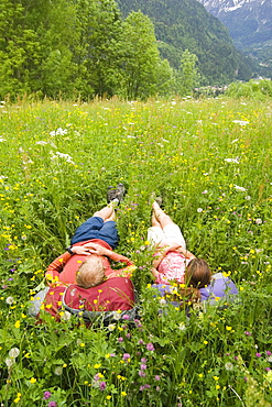 Two hikers rest in a field of flowers in the countryside near Chamonix, France.