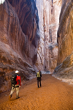 Three hikers in canyon, Arches National Park, Moab, Utah.