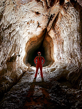 A cave explorer poses in a tube in a cave in Mulu National Park