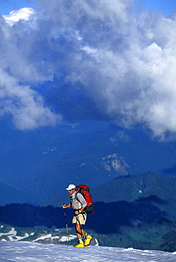 Climber in shorts with trekking poles summits Mount Rainier, Washington.