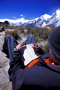 A young male working on a crossword puzzle the Cordillera Blanca, Peru.