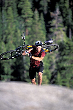 A man carrying his mountain bike up a hill in Lake Tahoe, California (Selective Focus).