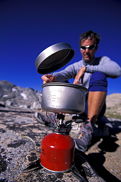 Man using a camp stove in Eastern Sierra Nevada mountains, California.