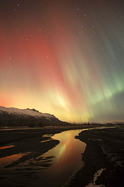 The aurora borealis (northern lights) shines with multiple colors above the Chugach Mountains in Alaska's Knik River Valley.