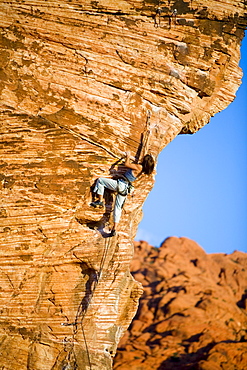 A women stretches to clip the draw on the crux while climbing.