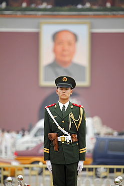 Soldier on guard on Tiananmen Square in Beijing in front of the Forbidden City and the big portrait of Mao Zedong