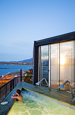 PUERTO NATALES, PATAGONIA, CHILE. A woman sits in an empty hot tub overlooking the waters surrounding Puerto Natales.