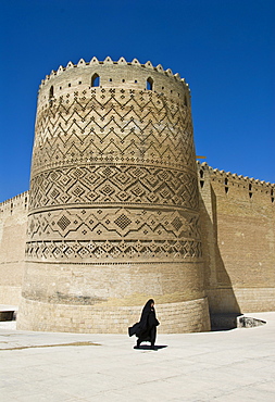 Muslim woman wearing a black veil in front of the tower of the Arg-e-Karim Khani fortress, Shiraz, Iran