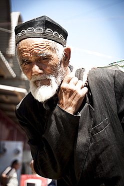 Old man carrying goods in the Osh street market of Kyrgyzstan