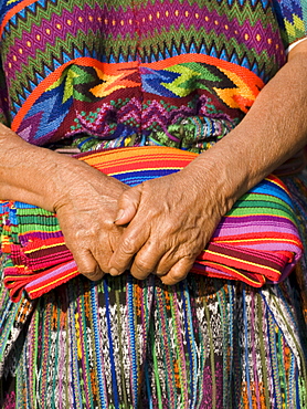 The hands of an indigenous Guatemalan woman holding traditional fabric.