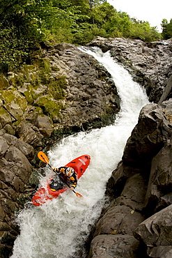 Overhead view of a kayaker going down a narrow and steep rapid.