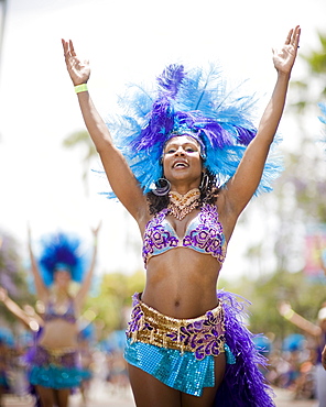 A Brazilian dancer performs at a parade in Santa Barbara. The parade features extravagant floats and costumes.