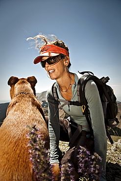 A woman  talks to her dog while taking a break from climbing a mountain, La Sals, Utah.