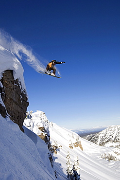 A male snowboarder jumps off a cliff in the Wyoming Backountry.