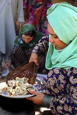 A woman scoops mantu, steamed dumplings stuffed with spiced meat, onto a plate to serve to guests, at a home in Mazar-i Sharif, Afghanistan