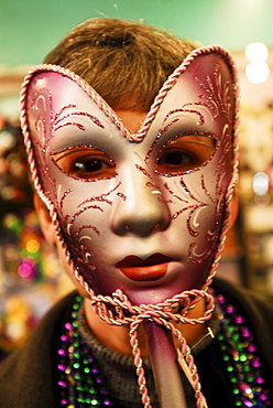 Woman holding a Carnival mask over her face.