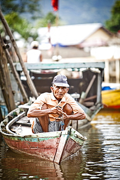 A man peers out from his small fishing boat near the dock in Sukadana, Indonesian Borneo.