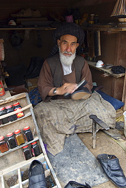 A Tajik man repairs and shines shoes in the bazaar of  Turghondi, a town on the border with Turkmenistan, in the northern part of Herat Province.