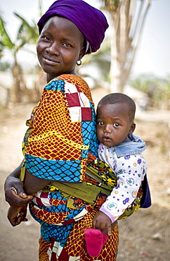 A young woman in the village  of Sakomedu carries her son on her back near the border with Guinea.