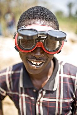 Young man wearing protective goggles while breaking rocks working at a gravel pit part of road construction on the  Voinjama - Foya road in Lofa county in Northern Liberia