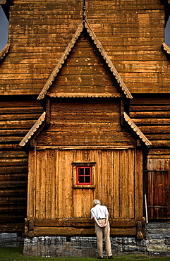 A man inspects the side of View of the exterior of Lom Stavkyrkje in Lom, Norway.