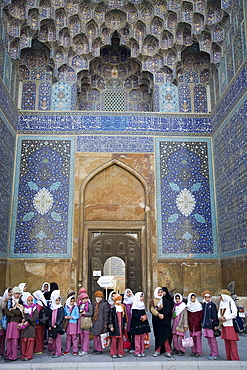 Esfahan, Iran - February, 2008: School girls dressed in pink visiting Imam Mosque. The 17th century mosque was built by Shah Abbas I and is considered one of the most beautiful in world with is blue-tile mosaic design and massive dome.