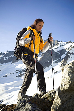 A Latina woman backpacks in the snowy mountains.