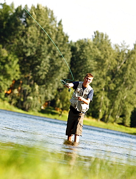 A teenage boy fly fishing in Swan River near Bigfork, Montana.