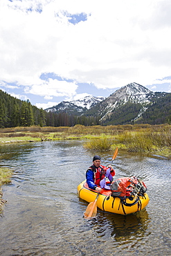 A young man paddles his small, inflatable raft on the upper reaches of the Salmon River in Idaho.