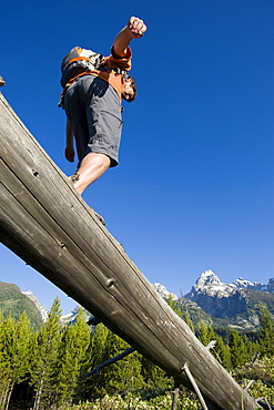 A young man hiker balances on an old log in the Grand Teton National Park, Wyoming.