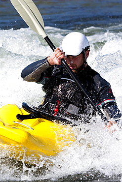 A male kayaker in a playboat paddles on the Clark Fork River, Missoula, Montana.