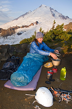 A woman cooking a meal while camping below Mount Baker, Mount Baker Wilderness, Bellingham, Washington.