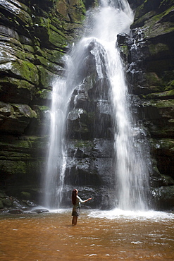 A woman observes a waterfall in Brazil.