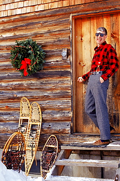 Paul Cate at ease and at home in front of the solar powered log cabin he and his family built and live in near Montpelier, VT.