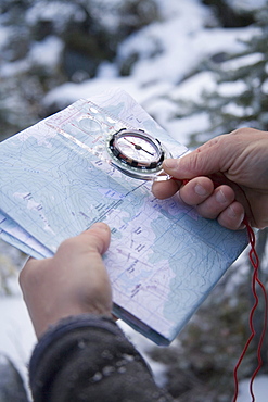 A male hiker checks his location with a compass and topographic map.