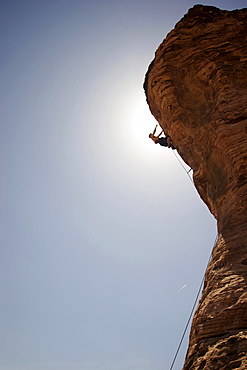 A rock climber ascends a red rock face in Nevada.