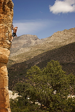 A rock climber ascends a red rock face in Nevada.