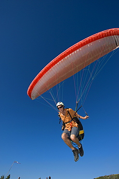 A paraglider lifts off the ground to begin his flight.